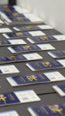 Luxury wedding passport invitation cards arranged on a table with navy blue covers, gold emblem detailing, and personalized boarding pass inserts for a destination wedding.