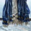 Blue customized logo lanyards with metal clips hanging in bulk for corporate distribution.