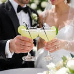 Bride and groom toasting margaritas with personalized wedding drink stirrers.